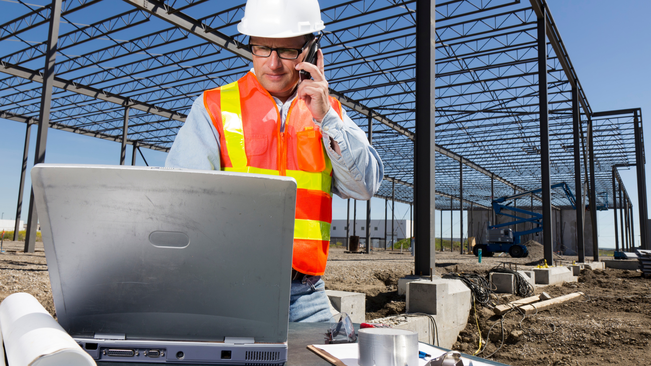 construction supervisor using laptop and mobile device